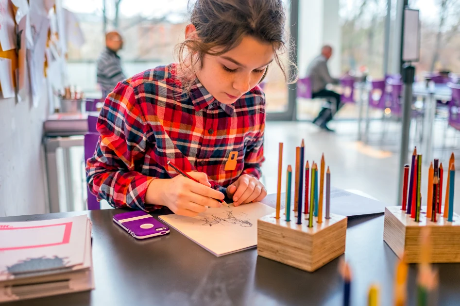Foto di una bambina che disegna con le matite colorate in un museo durante un laboratorio didattico